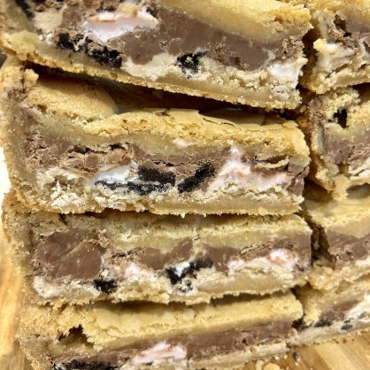 A stack of cookie slices, filled with chocolate, marshmallows and oreos.