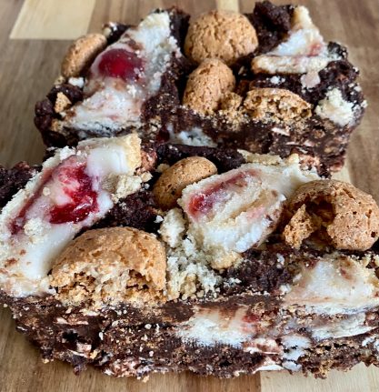 Two square slices of chocolate dessert with biscuit pieces and a layer of red fruit filling.