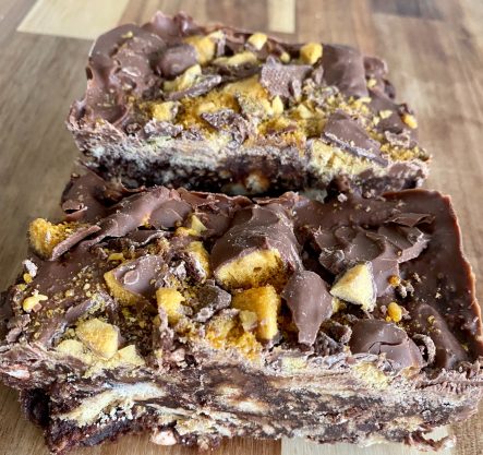 Chocolate dessert bars topped with crushed nuts and chocolate pieces.